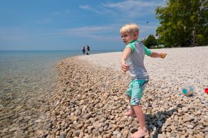 A boy winds up to throw a rock into the water at one of Mackinac Island's many beaches that are great for stoneskipping
