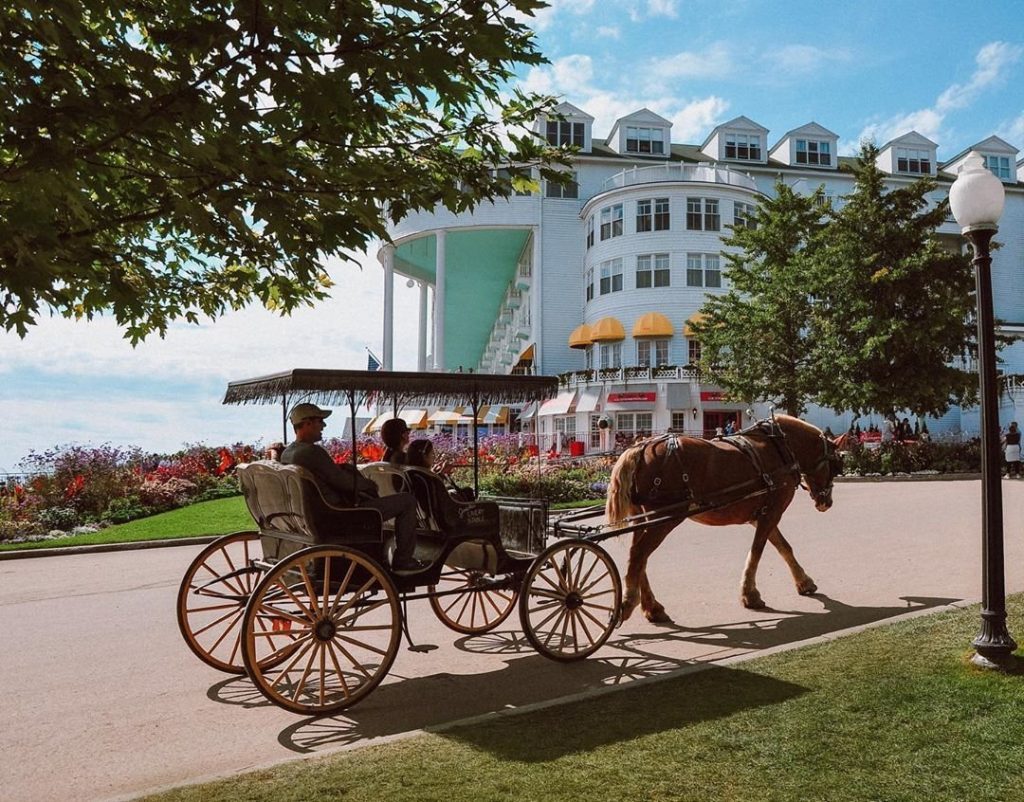 A drive-it-yourself horse carriage on Mackinac Island passes by Grand Hotel as it makes its way up the hill