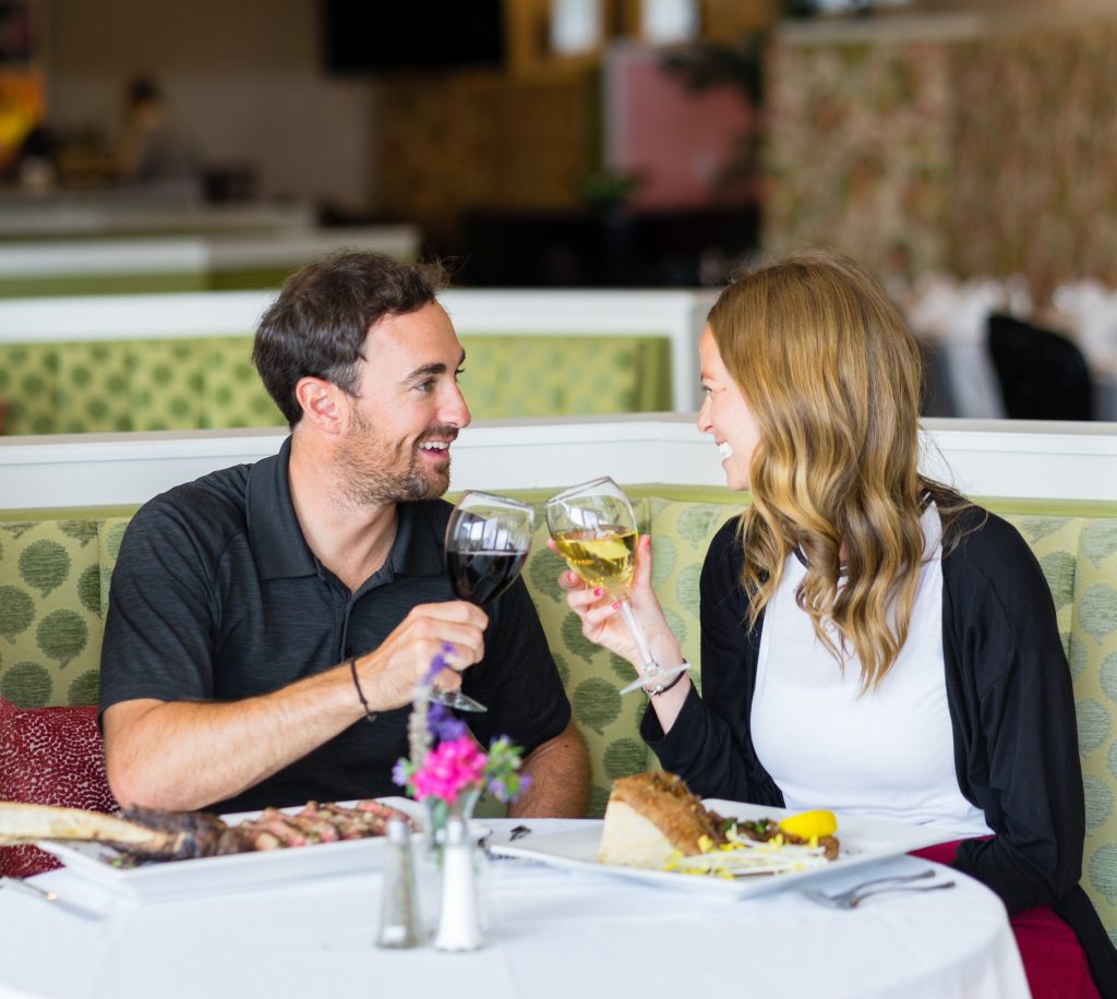 A couple clink wine glasses while sharing a delicious meal at 1852 Grill Room restaurant on Mackinac Island