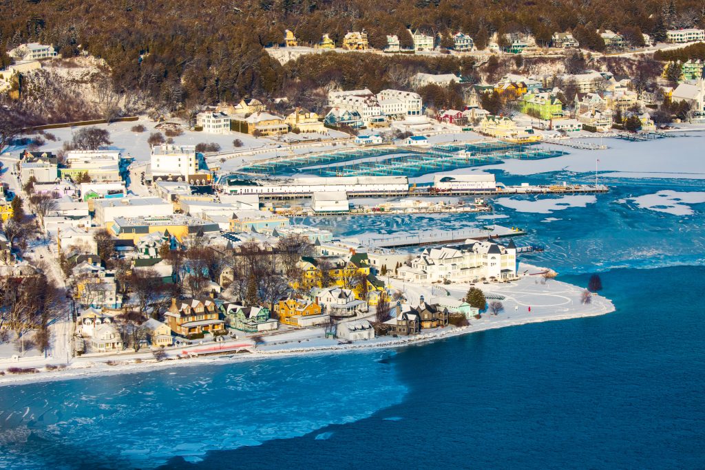 An aerial winter view of snow-covered downtown Mackinac Island and an icy Mackinac Island harbor