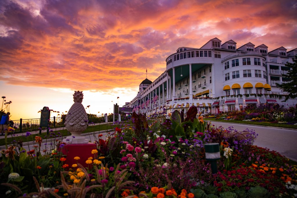 The sun sets behind Mackinac Island’s stately Grand Hotel with flowers blooming in the foreground