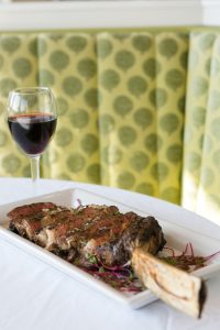 An appetizing plate of meat and veggies with a glass of wine at 1852 Grill Room restaurant on Mackinac Island