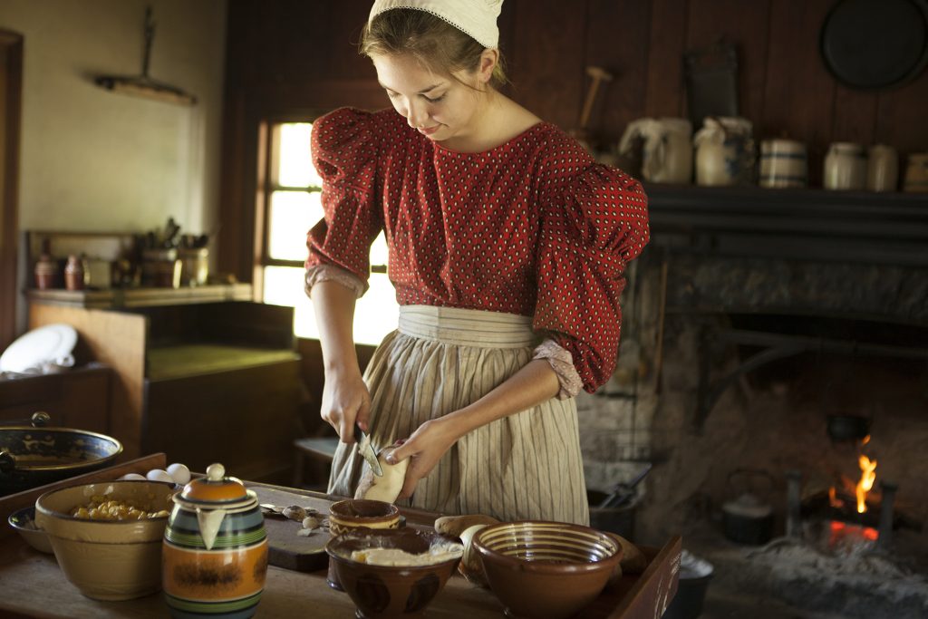A historical interpreter prepares food in the kitchen of the Biddle House Mackinac Island Native American Museum on Mackinac Island