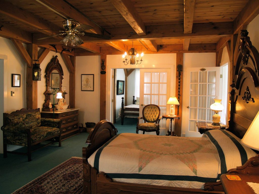 A bedroom at Haan’s 1830 Inn on Mackinac Island features period furniture and a wooden beam ceiling