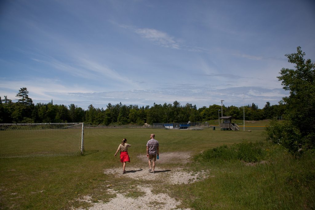 Two people walk along a dirt path into Mackinac Island's Great Turtle Park