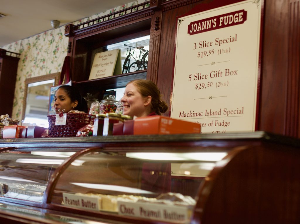 Two workers stand behind the counter at Joann's Fudge on Mackinac Island