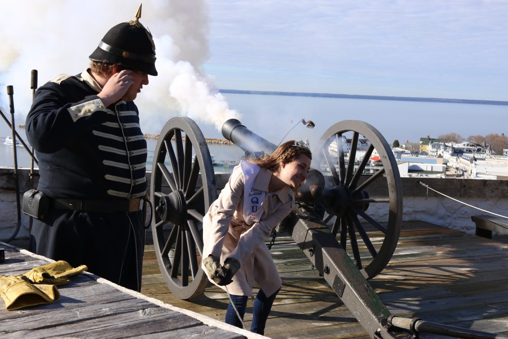 A festival queen blasts the cannon at Mackinac Island's historic Fort Mackinac as a historical interpreter watches