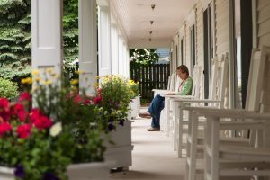 A woman relaxes in a chair with a book on a quiet Mackinac Island porch