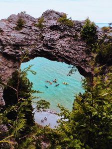 A flotilla of kayaks pauses in the water beneath Mackinac Island's iconic Arch Rock