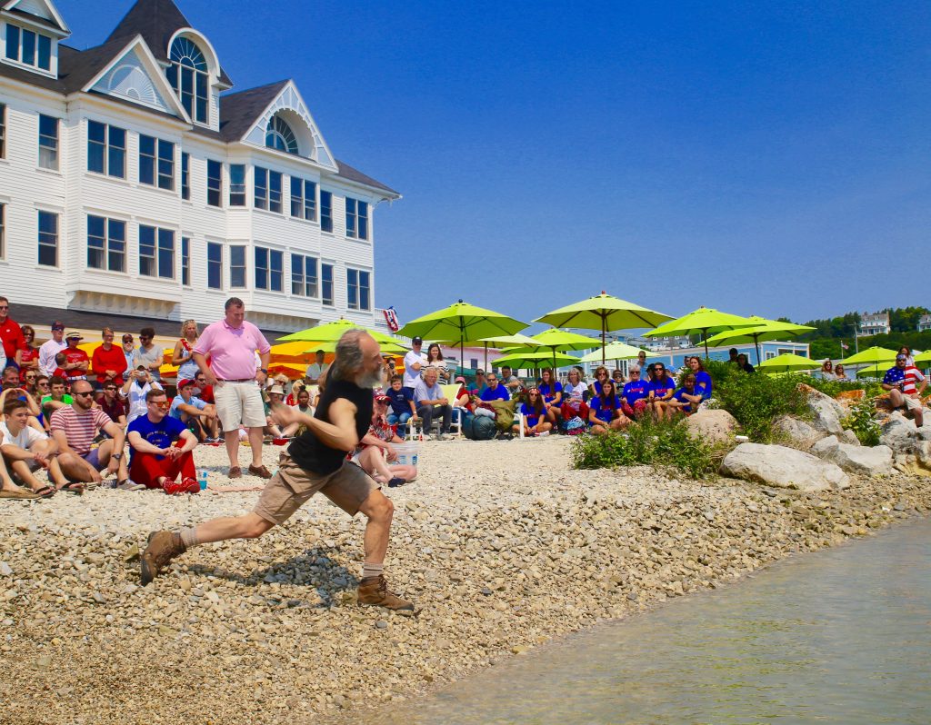 Kurt Steiner throws a stone into the water as a crowd watches during Mackinac Island’s annual stoneskipping competition