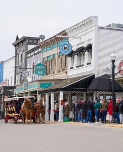 Mackinac Island visitors wearing hats and coats line up to buy tickets for horse-drawn carriage tours in early spring