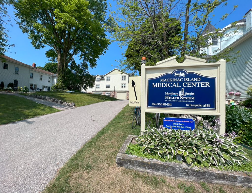 A Mackinac Island Medical Center sign with an arrow pointing up a street toward the building