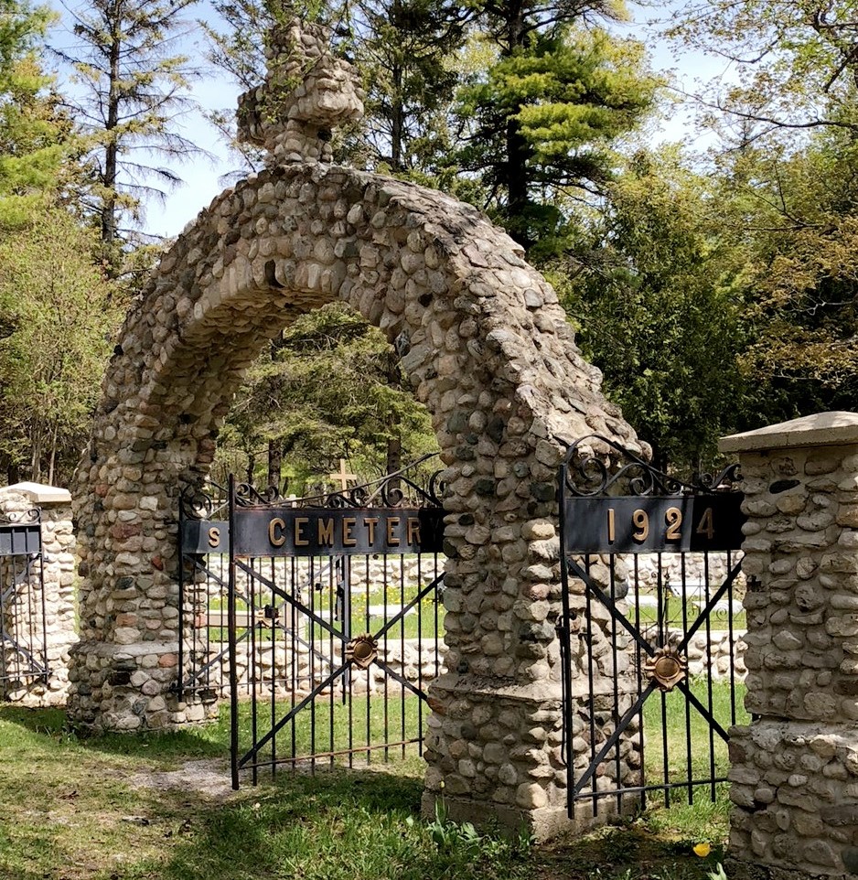 A stone arch with cross marks the entry to Ste. Anne's Cemetery on Mackinac Island