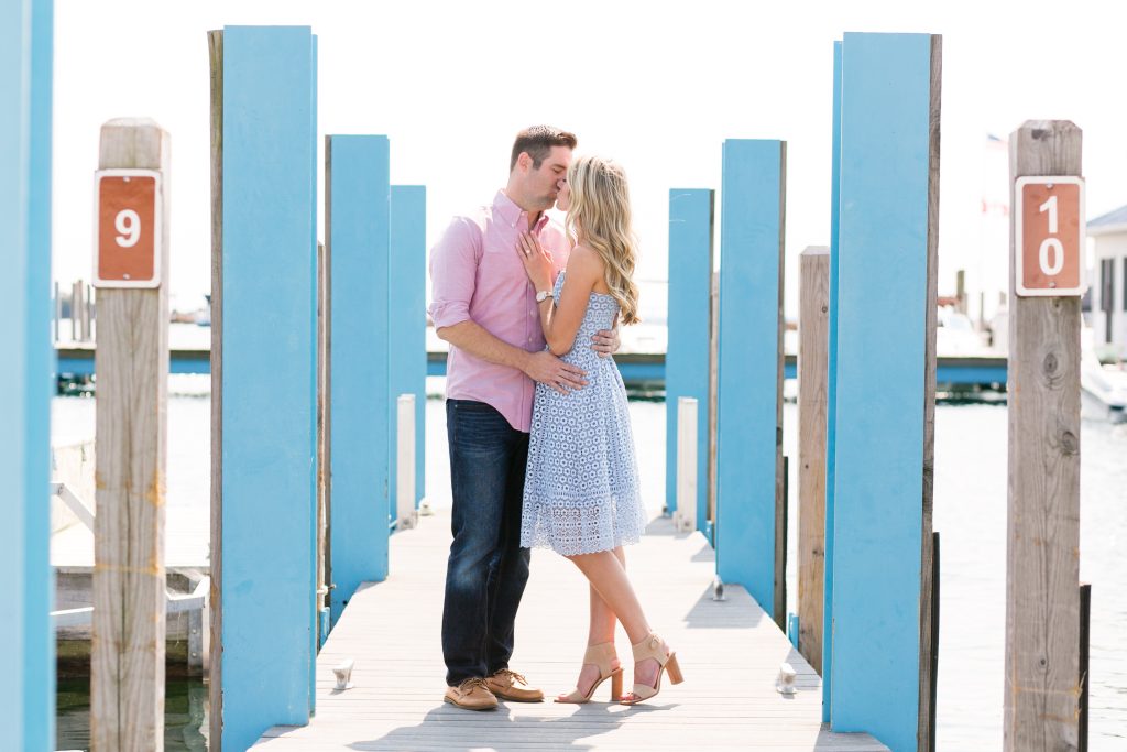 A young couple kisses while standing in the middle of a Mackinac Island dock over the water