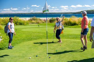 A woman celebrates making a putt while playing the Greens of Mackinac golf course with friends at Mackinac Island's Mission Point Resort