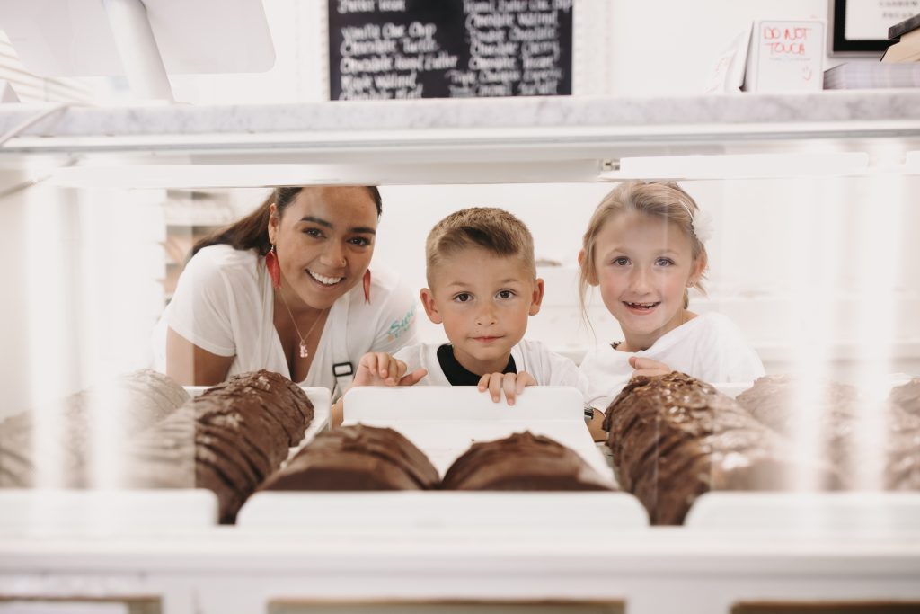 A Mackinac Island fudgemaker and two children peer through the counter display of fudge during the Mackinac Island Fudge Festival