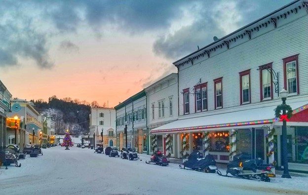 Daytime winter scene of Main Street on Mackinac Island lined with snowmobiles and a Christmas tree in the middle