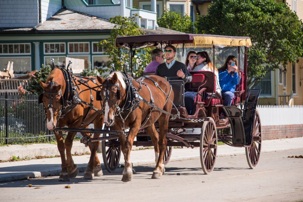 A horse-drawn carriage takes two couples on a tour of Mackinac Island