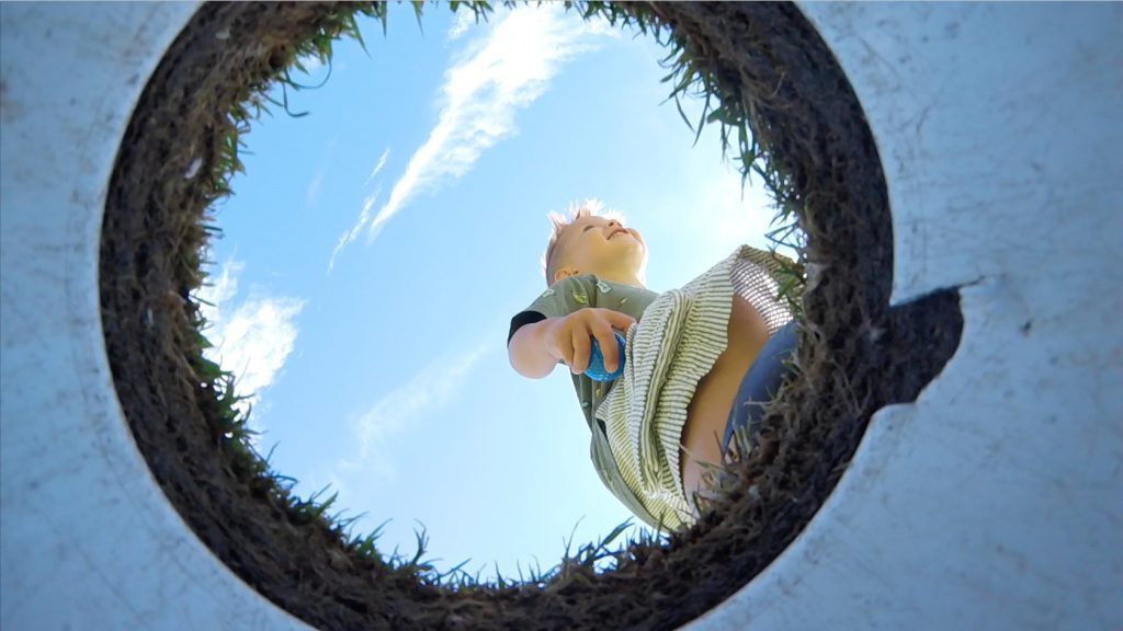 A view from the bottom of the cup of a young boy holding a golf ball on the Greens of Mackinac putting course at Mackinac Island's Mission Point Resort 