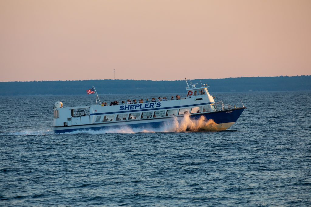 A Shepler’s ferry boat glides through the water off Mackinac Island at sunset