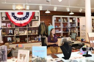 A cashier smiles behind the counter of the museum store at Mackinac Island’s historic Fort Mackinac