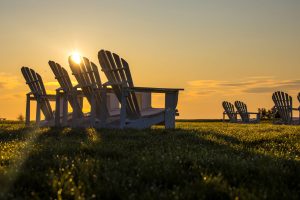 The sun rises over a lawn full of empty Adirondack chairs on the great lawn at Mission Point Resort on Mackinac Island