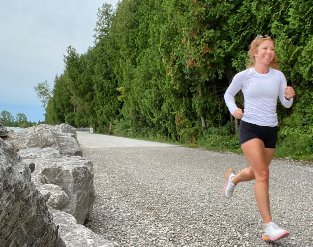 A young woman runs along the road that circles Mackinac Island by the water