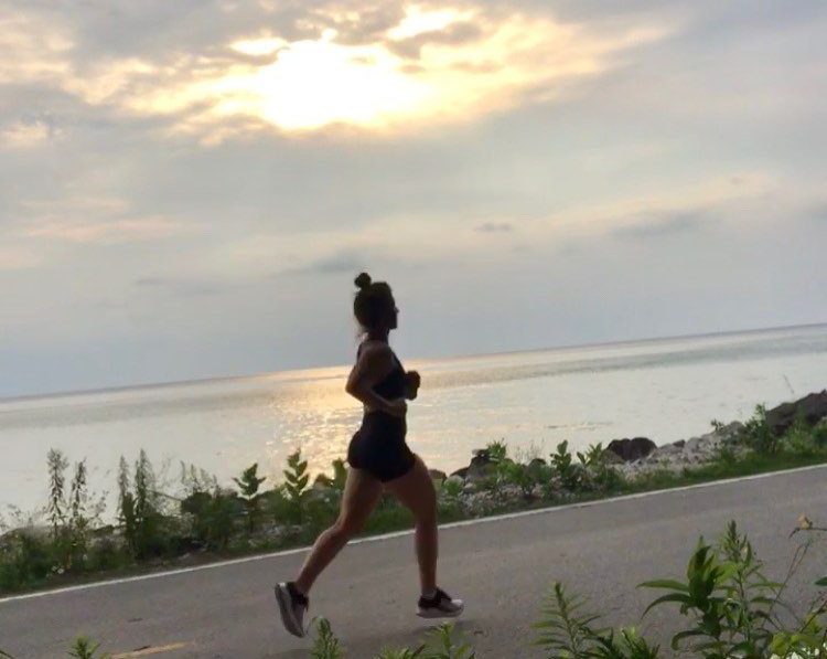 A woman runs along car-free M-185 on Mackinac Island as the sun rises over the water on the lake