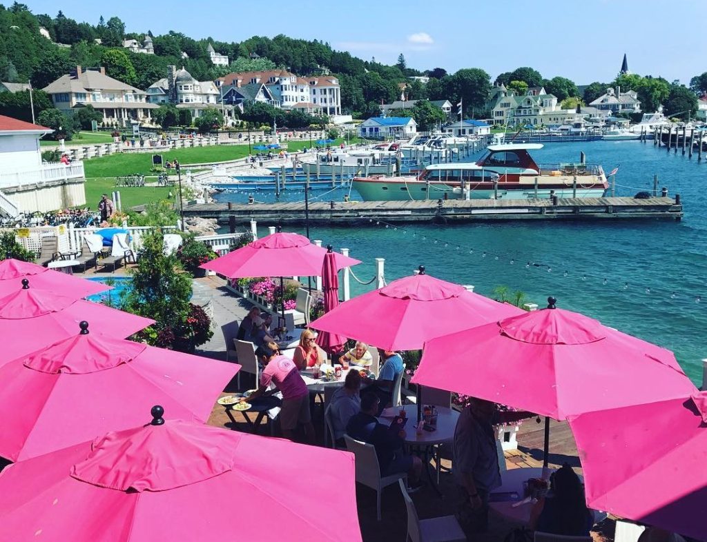 Pink umbrellas shade the dining tables on the outdoor patio at Mackinac Island's Pink Pony restaurant on the water near the marina