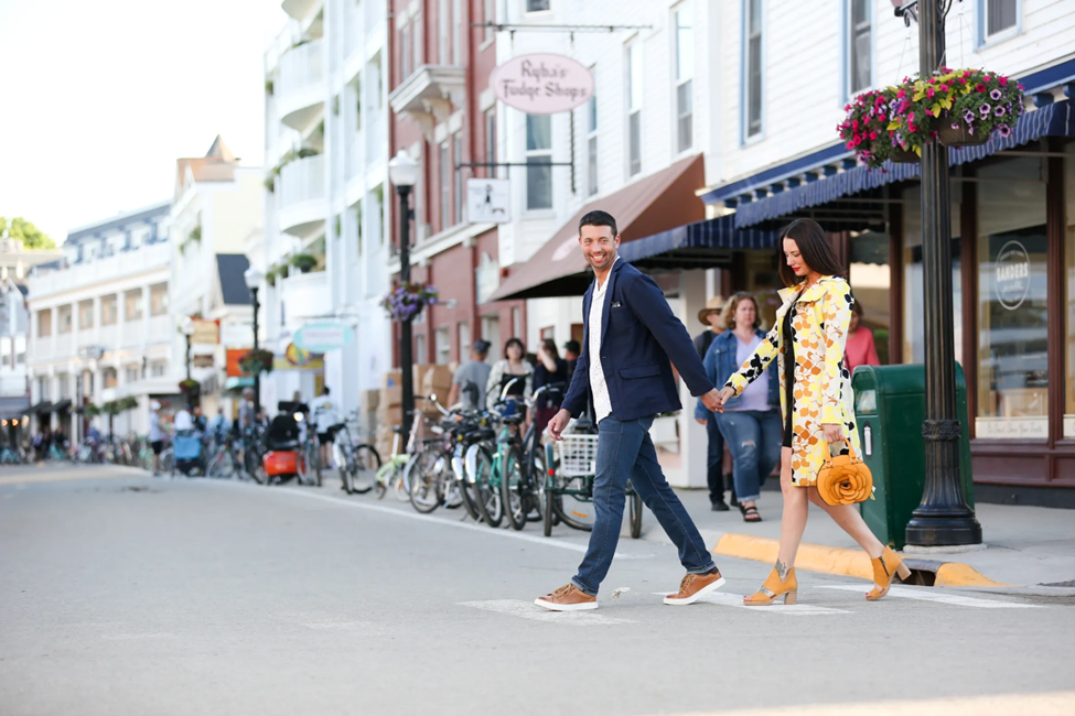 A young couple holds hands while crossing a downtown Mackinac Island street lined with bicycles
