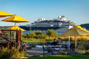 A cruise ship floats on the water near one of the outdoor dining patios at Mackinac Island’s Mission Point Resort