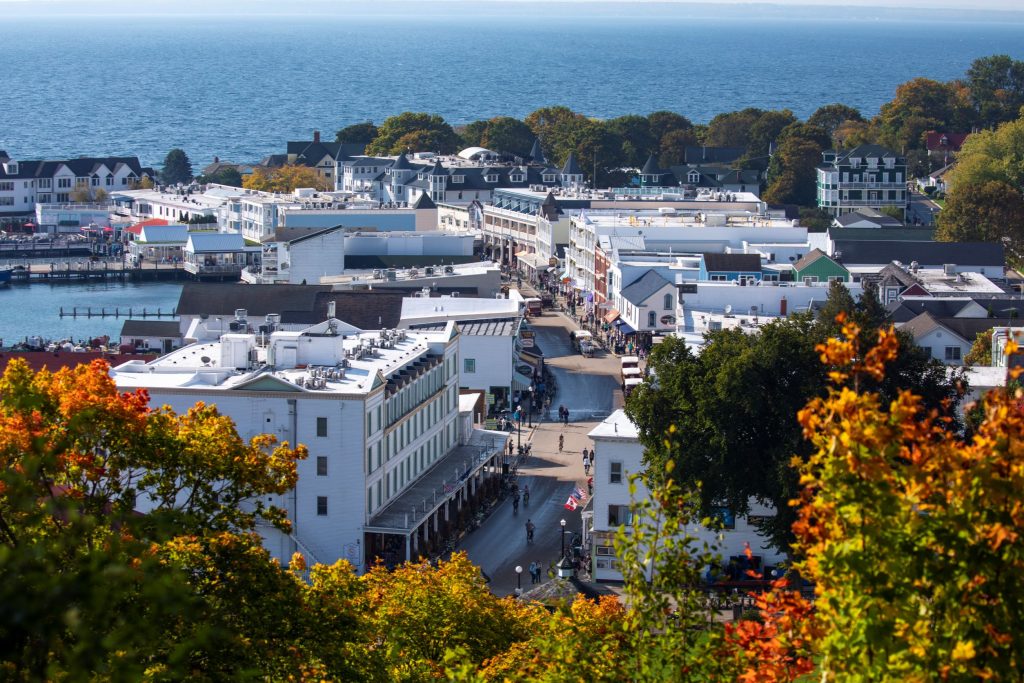 A view of downtown Mackinac Island and the water beyond from the bluff above with fall colors in the foreground
