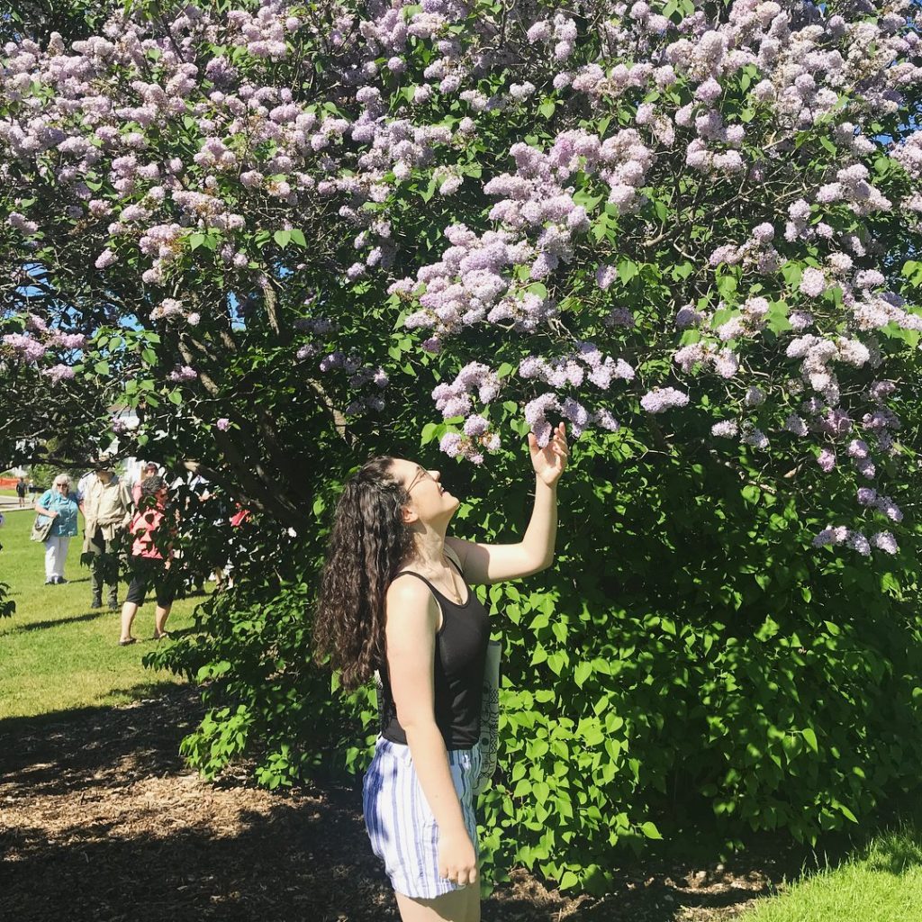A young woman smells the sweet scent of lilacs on a particularly large stem on Michigan's Mackinac Island