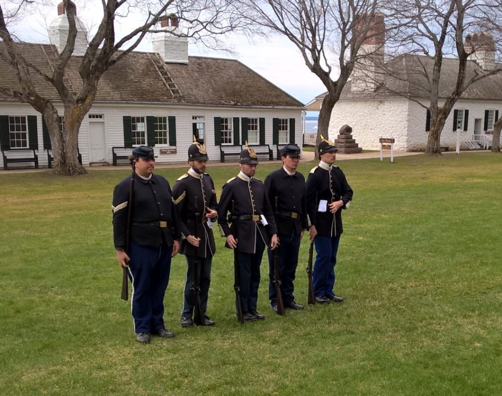 A handful of historical interpreters line up for a demonstration on the grounds of Mackinac Island's historic Fort Mackinac