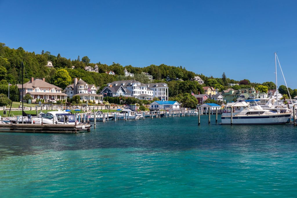 Cottages and hotels line the Mackinac Island shore from a perspective amid the boats on the water in the harbor