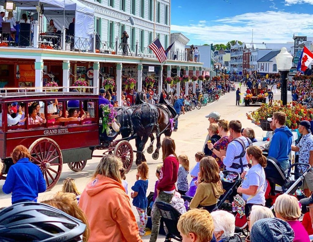 A horse-drawn carriage makes its way down Main Street during the Mackinac Island Lilac Festival Grand Parade