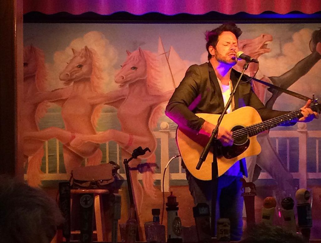 Musician on Stage Playing Guitar and Singing Into Microphone During Concert on Mackinac Island