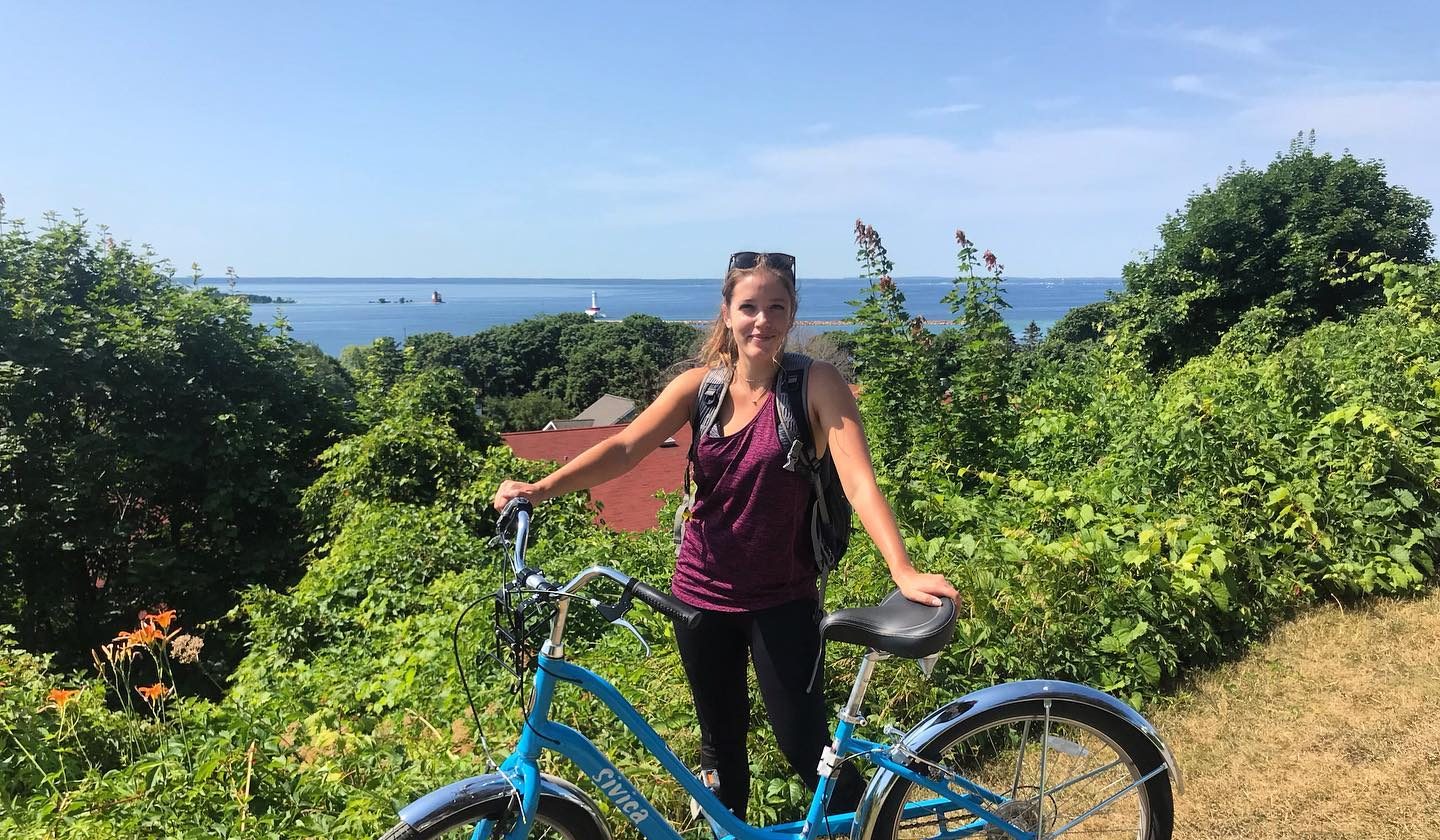 A woman with a bicycle stands at a high vantage point on Mackinac Island