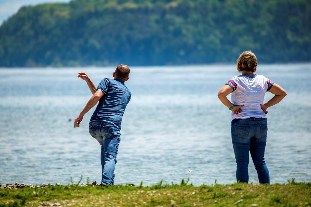 A man skips a stone into the water off Mackinac Island as a woman stands and watches nearby