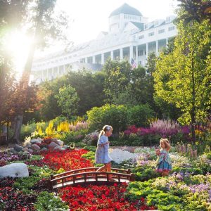 Two young girls walk across a bridge amid a host of colorful flowers in the Secret Garden at Mackinac Island’s Grand Hotel
