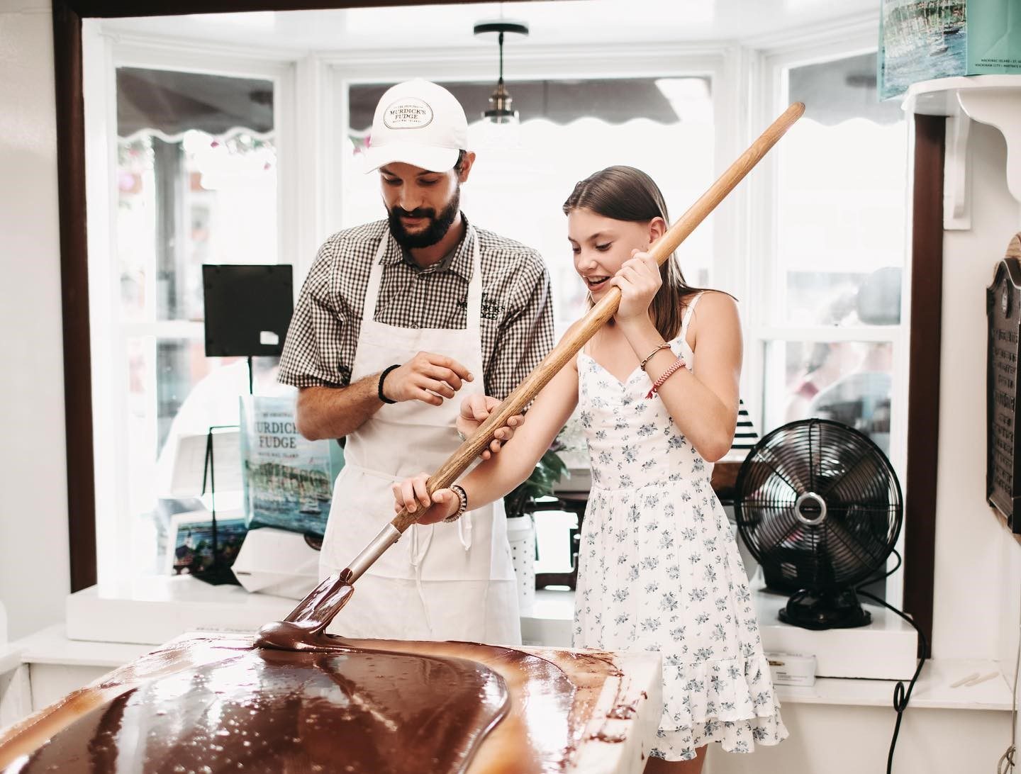 A fudgemaker on Mackinac Island teaches a young woman how to mold liquid fudge into a loaf during the Mackinac Island Fudge Festival