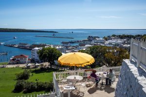 A yellow umbrella shades an outdoor dining table at the Fort Mackinac Tea Room high above the Mackinac Island harbor