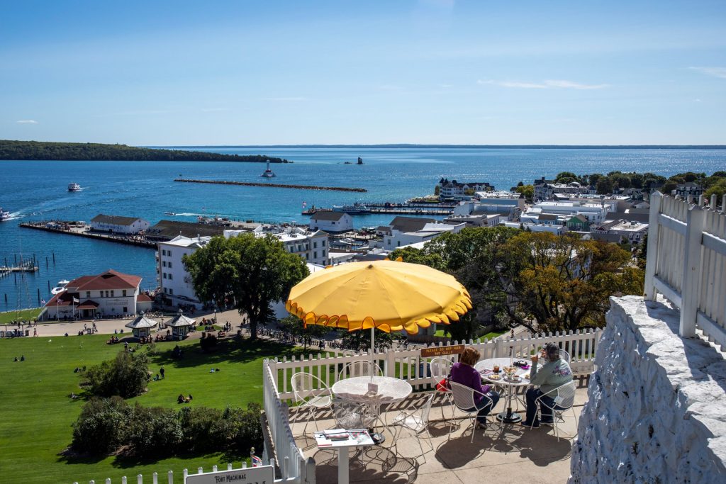 Two people dine under a yellow umbrella at the Fort Mackinac Tea Room overlooking the gorgeous Mackinac Island waterfront
