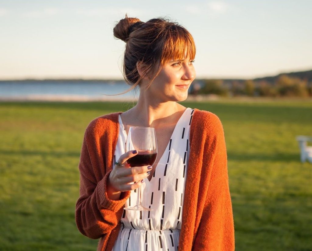 A young woman holds a glass of wine at sunset on the lawn at Mackinac Island’s Mission Point Resort